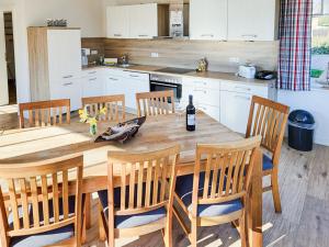 a kitchen with a wooden table with chairs and a bottle of wine at Ferienhaus Kranichnest in Breege +21 photos