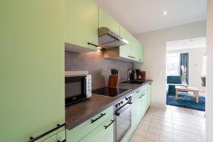 a kitchen with green cabinets and a microwave at Commodore Whg 15 in Grömitz