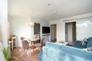 a living room with a blue couch and a table at Commodore Whg 15 in Grömitz