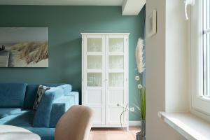 a living room with a blue couch and a white cabinet at Commodore Whg 15 in Grömitz