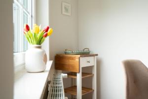 a table with a vase of flowers next to a window at Commodore Whg 15 in Grömitz +9 photos