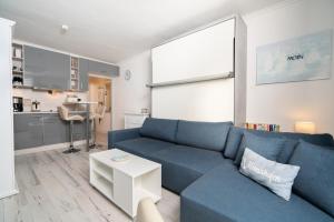 a living room with a blue couch and a kitchen at Solymar Whg 29 in Grömitz