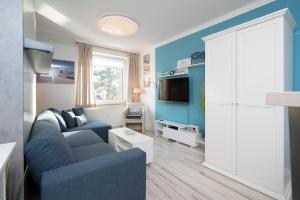 a living room with a couch and a tv at Solymar Whg 29 in Grömitz +8 photos