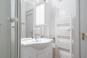 a white bathroom with a sink and a mirror at Solymar Whg 29 in Grömitz