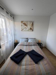 a bedroom with a bed with two black shirts on it at Maison de Vacances Mon Cocon Bordelais in Villenave-dʼOrnon