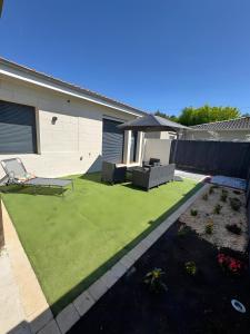 a backyard with green grass and a house at Maison de Vacances Mon Cocon Bordelais in Villenave-dʼOrnon