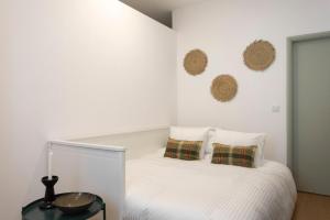 a white bedroom with a bed with two pillows at Casa em bairro típico de Aveiro in Aveiro