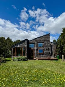 a small house with a brick facade on a grass field at Casa Arrayan in Puerto Varas