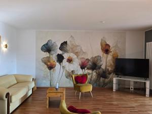 a living room with a painting of flowers on the wall at Exklusive Ferienwohnung Bad Salzschlirf - direkt am Waldrand - großer Garten kompett umzäunt - Hunde willkommen - 2 private Stellplätze in Bad Salzschlirf