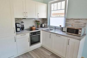 a kitchen with white cabinets and a microwave at Haus Fischerstraße 6a in Grömitz