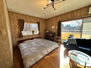 a bedroom with a bed and a couch and a window at 一棟丸ごと貸別荘あそべるごでぃふーぞ in Takamori