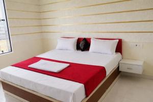 a bedroom with a large white bed with a red blanket at Pushp Vatika Hotel & Resort in Thālera