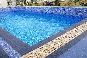 a swimming pool with blue water and a wooden bench at Pushp Vatika Hotel & Resort in Thālera