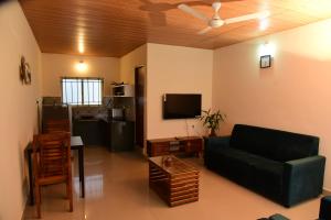 a living room with a couch and a tv at Nirantara Luxury Service Apartment in Gonikoppal