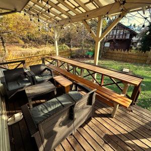 a wooden deck with a bench and chairs on it at 一棟丸ごと貸別荘あそべるごでぃふーぞ in Takamori