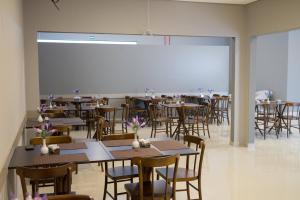 a classroom with tables and chairs and a large screen at Hotel Vila Verde in Penápolis