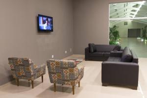 a living room with a couch and chairs and a tv at Hotel Vila Verde in Penápolis