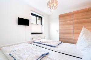 a bedroom with two beds and a tv on the wall at Titania Whg 10 in Grömitz