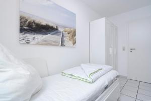 a white room with a bed and a painting on the wall at Titania Whg 10 in Grömitz