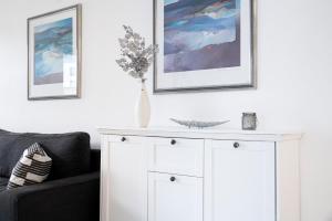 a white cabinet in a living room with two pictures on the wall at Titania Whg 10 in Grömitz +19 photos