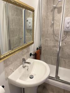 a bathroom with a sink and a shower and a mirror at Weymouths Coastal Nook in Weymouth