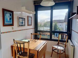 a kitchen with a wooden table and two chairs and a window at Babilonia, apartamento en Llanes tranquilo y céntrico a 150m de la playa del Sablón in Llanes