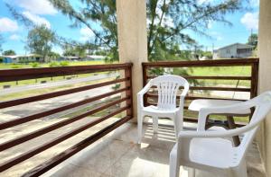 two white chairs sitting on a porch with a view at Serene Escape - Central & Modern in Christ Church +1 photo
