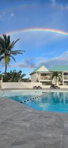 a rainbow over a swimming pool in front of a beach at Magnifique appartement vue mer Oyster Pond in Saint Martin