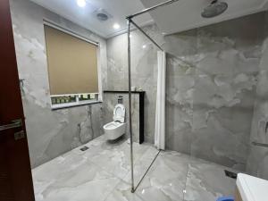 a bathroom with a toilet and a glass shower at The 104-H in Faisalabad