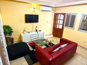 a living room with a red couch and a tv at Appartement Meublé 3 Chambres in Douala