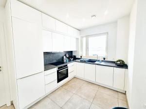 a white kitchen with white cabinets and a window at Relaxed City 1BR Apartment in Luxembourg
