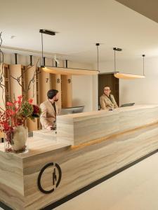 three men standing at a reception desk in a lobby at Il Leon D'Oro Bari - by Farace Hotels in Bari