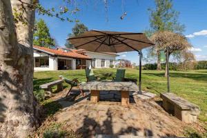 a picnic table and bench with an umbrella in a yard at B&B Casa Danoi in Trinità