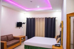 ein Zimmer mit einem Bett, einer Couch und violettem Licht in der Unterkunft Hotel Al Azeem in Ayubia