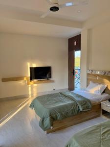 a bedroom with a bed and a flat screen tv at Xsquare Hotel in Garubhāsa