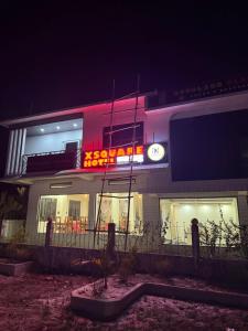 a building with a neon sign on it at night at Xsquare Hotel in Garubhāsa