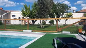 a swimming pool with a wooden fence around it at Canto del DORMILERO in San Cristóbal de la Vega