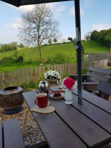 a picnic table with a cup of coffee and flowers on it at Cabin Retreat with Beavers on Shropshire Hills in Newcastle