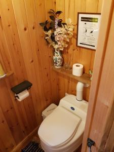 a bathroom with a toilet and a vase of flowers at Cabin Retreat with Beavers on Shropshire Hills in Newcastle
