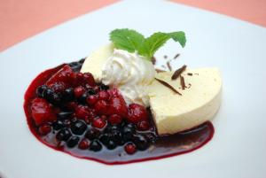 a piece of cheesecake with fruit on a white plate at Guest House Gostišče Jutriša in Rogatec