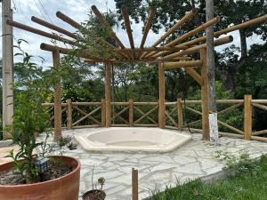 a hot tub in a garden with a wooden pergola at Chácara Cristo Rei in Senador Canedo