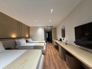 a hotel room with three beds and a flat screen tv at Rich Hotel in Pogradec