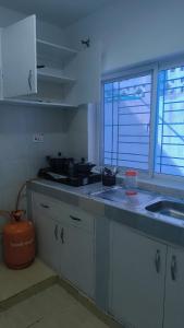a kitchen with white cabinets and a sink and two windows at NyaliHomes in Mombasa