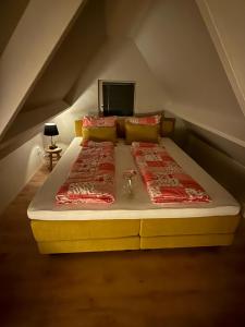a large bed in a attic with two red pillows at ‘t Bakhuis in Oostelbeers