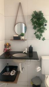 a bathroom with a sink and a mirror and a toilet at Quarto Aconchego Nordestino in Aracaju