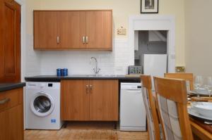 a kitchen with a sink and a washer and dryer at Secret Coast Getaway in Tighnabruaich +12 photos