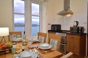 a kitchen with a table with plates and wine glasses at Secret Coast Getaway in Tighnabruaich