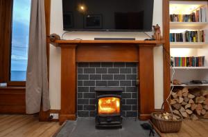 a fireplace in a living room with a tv above it at Secret Coast Getaway in Tighnabruaich