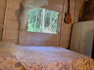 a bedroom with a bed with a window and a guitar at Canto da Águia in Ouro Preto