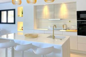 a white kitchen with a sink and white stools at Villa Concarella Di Conca in Conca